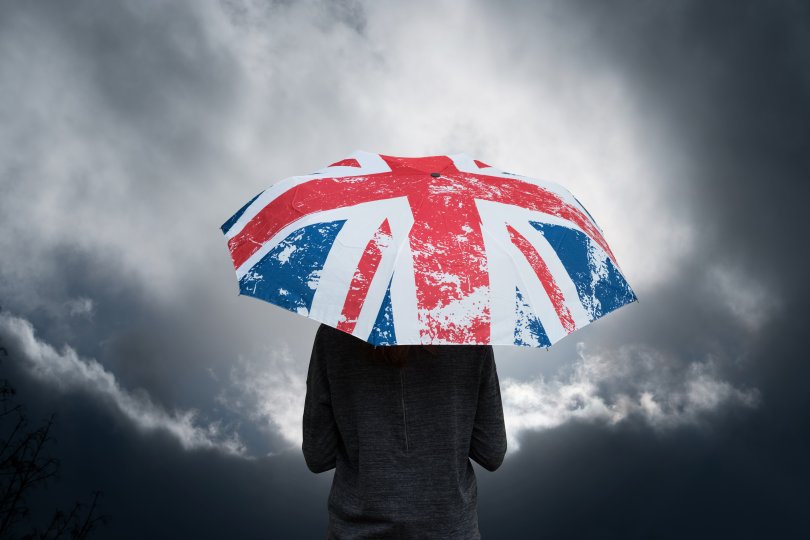 Silhouette carrying an umbrella with a British motif in the rain.
