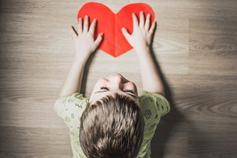 Photo d'un enfant tenant un cœur en papier (pas un vrai)