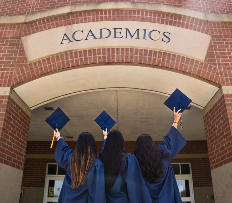 young graduates in front of the door of an academy