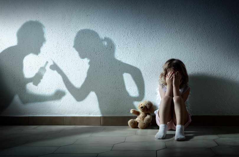 enfant pleurant alors que ses parents se déchirent, symbolisés par des ombres