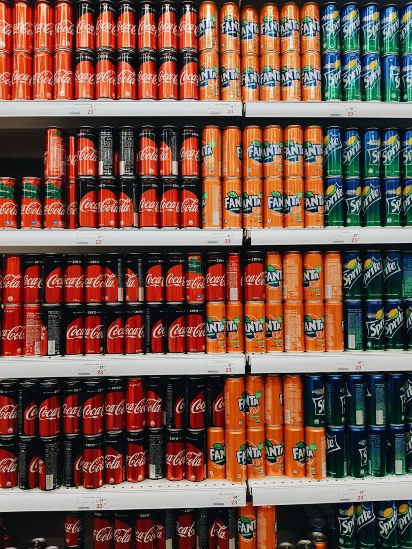 Supermarket shelf filled with canned soda.