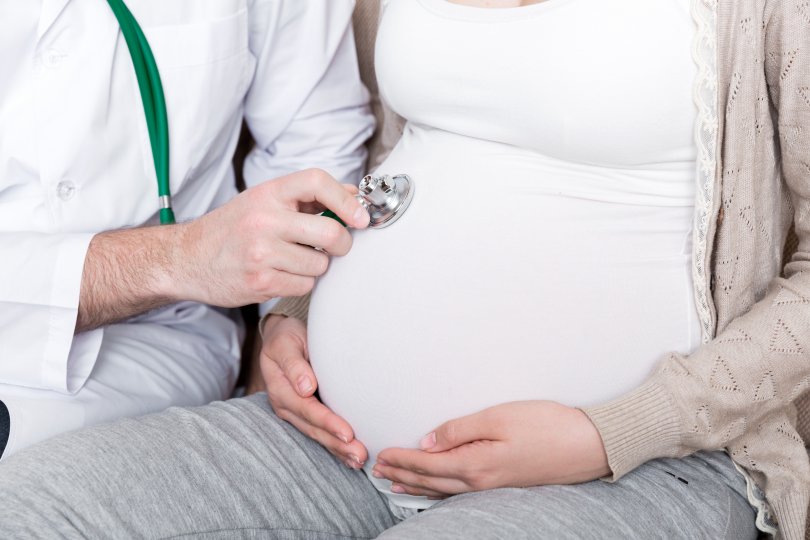 pregnant woman's belly with a doctor's hands on it.