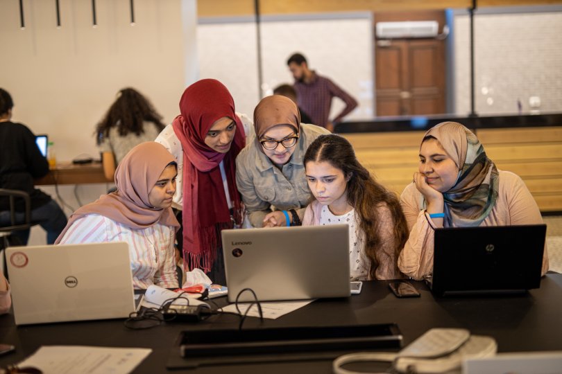 group of women with a younger student staring at a computer