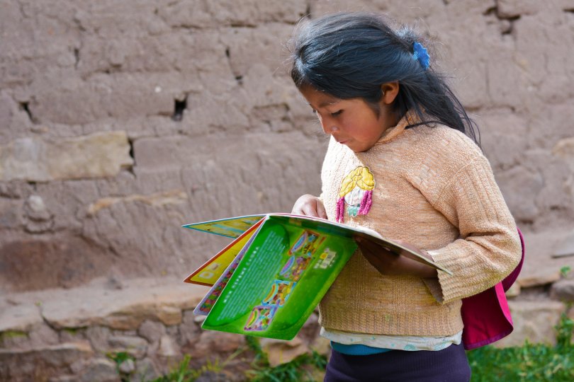 Native american little girl reading book in the countryside. 