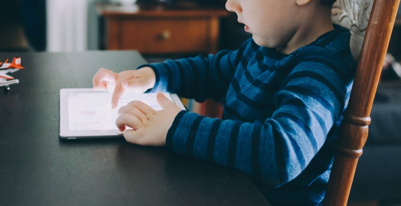 Landscape shot of a child hypnotised by a tablet screen.