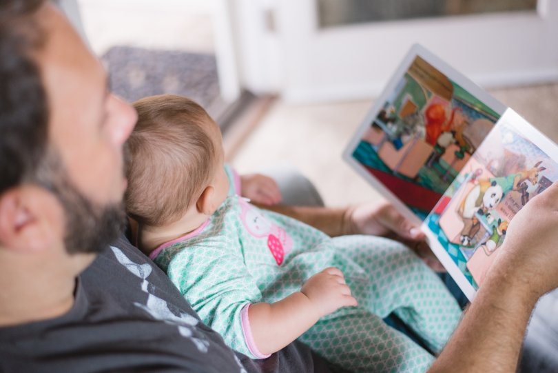 A child on his father's lap reading a book