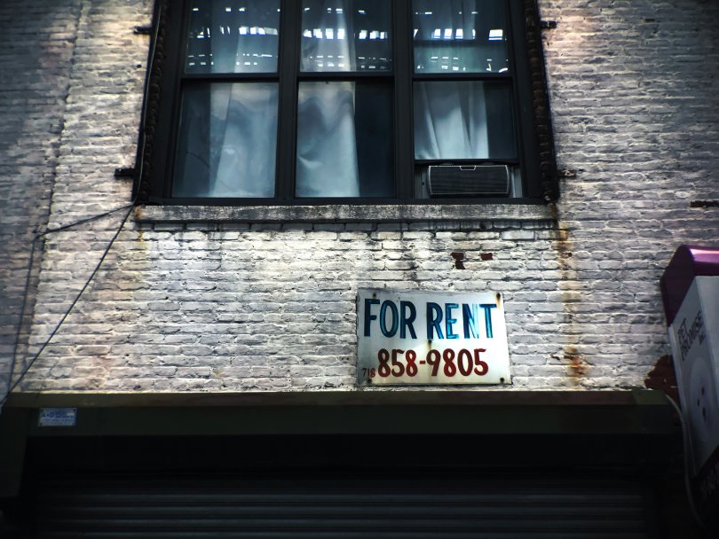 a sign indicating that an apartment is available for rent under a window.