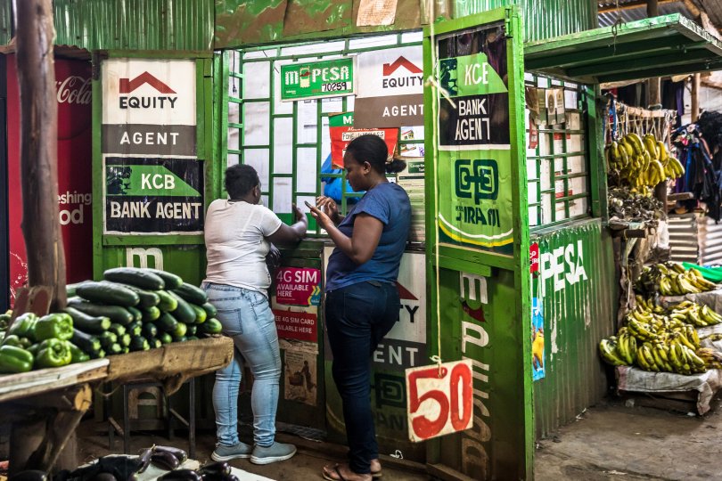 Customers use M-pesa services at a kiosk in Toi Market, an open air market and favorite spot to pick up second hand home goods, clothes, shoes, or just fresh fruit and vegetables in Nairobi.