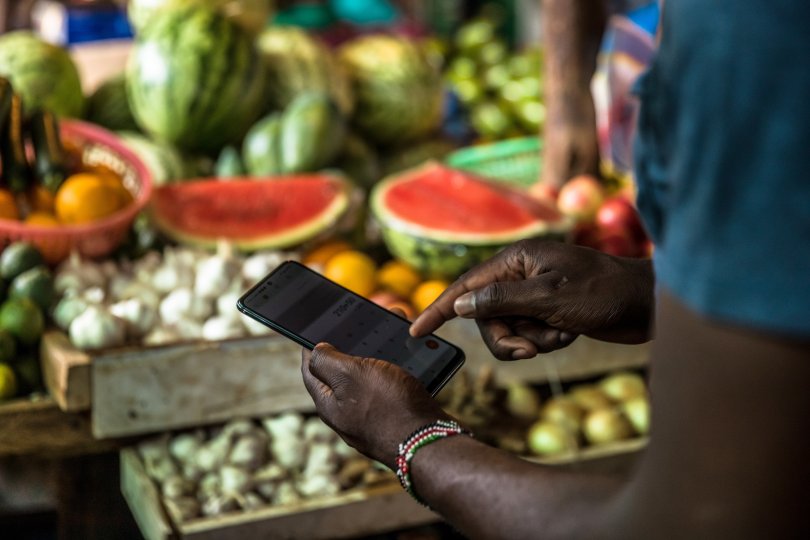A customer uses his phone to make a payment at Toi Market, an open air market and favorite spot to pick up second hand home goods, clothes, shoes, or just fresh fruit and vegetables in Nairobi, Kenya.