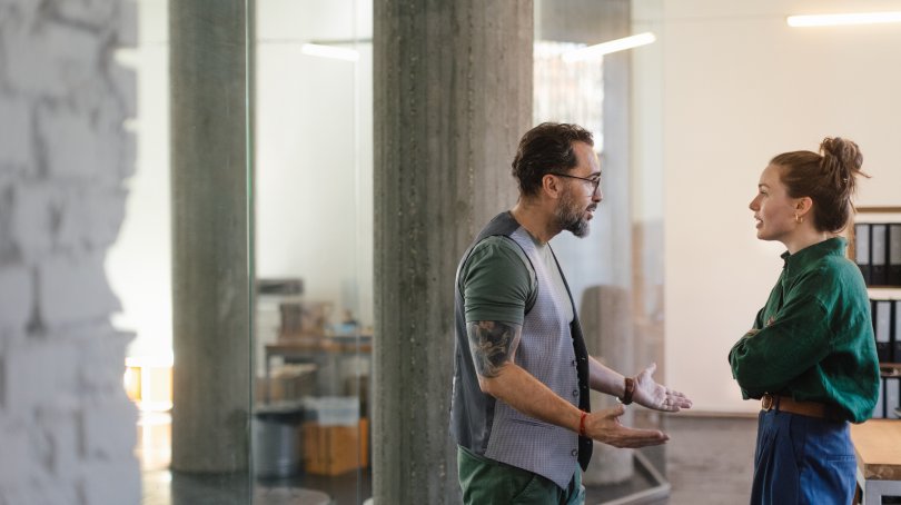 Une jeune femme et un homme en train de se disputer dans un bureau. 