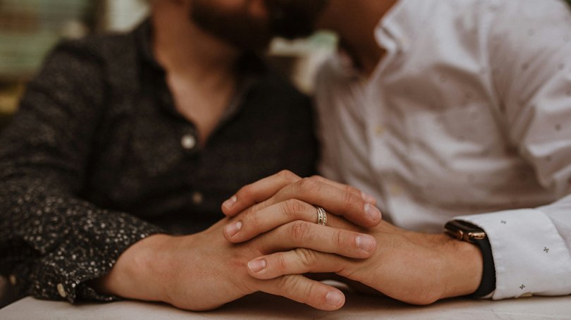 Two men kissing and holding hands