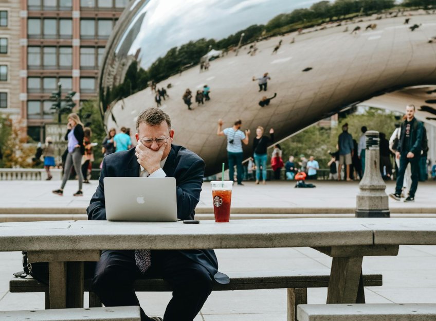 Un homme en tenue de ville travaillant sur son ordinateur assis à une table à Chicago. Photo © Tim Gouw via Pexels